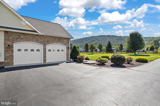 view of side of property with a mountain view, a garage, and a lawn