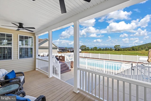 wooden terrace with a fenced in pool and ceiling fan