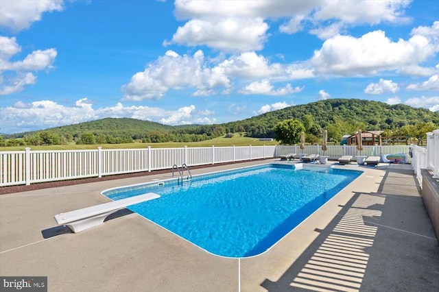 view of swimming pool featuring a diving board, a patio, and a mountain view