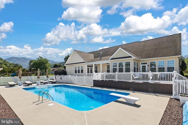 view of swimming pool with a deck with mountain view, a patio area, and a diving board