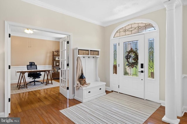 foyer entrance with decorative columns, hardwood / wood-style flooring, and crown molding