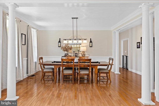 dining space with a healthy amount of sunlight, decorative columns, and light hardwood / wood-style floors