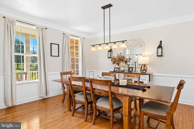 dining space with ornamental molding and light hardwood / wood-style flooring