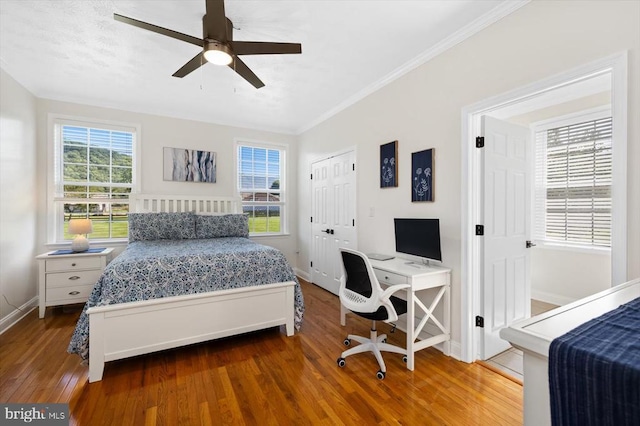 bedroom with crown molding, ceiling fan, wood-type flooring, and multiple windows