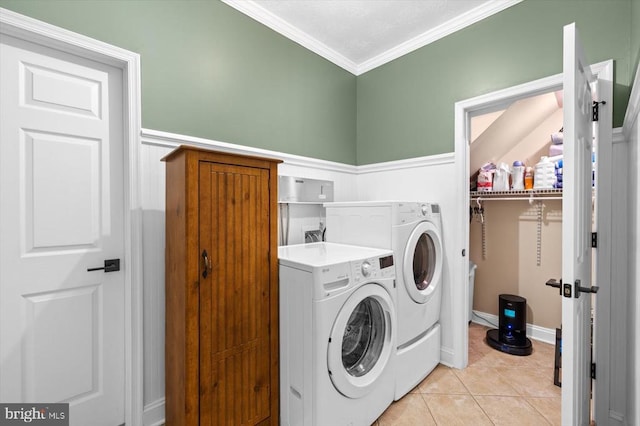 laundry area featuring light tile patterned floors, washing machine and clothes dryer, and ornamental molding