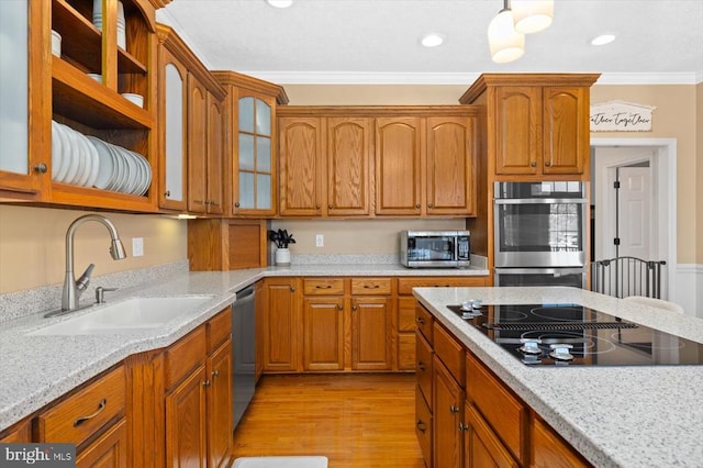 kitchen with light wood-type flooring, light stone countertops, stainless steel appliances, sink, and ornamental molding