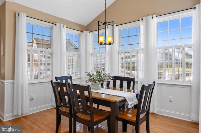 dining space with lofted ceiling, light wood-type flooring, and a chandelier