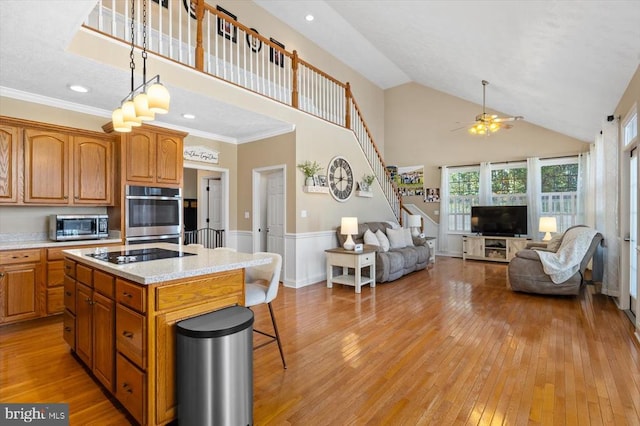 kitchen with a breakfast bar area, light hardwood / wood-style flooring, a center island, ornamental molding, and ceiling fan