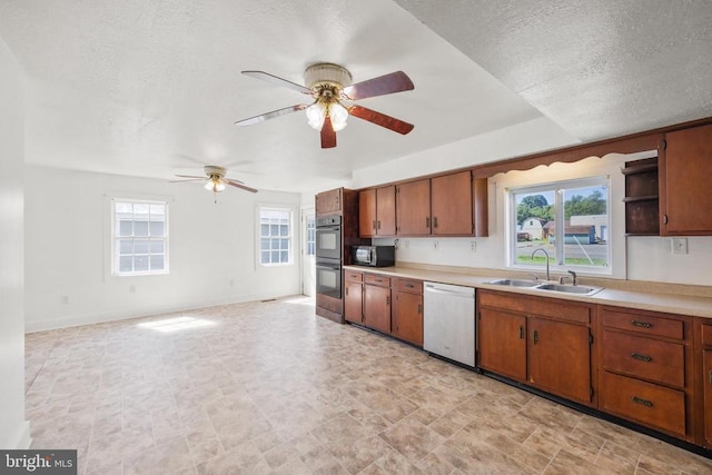 kitchen featuring white dishwasher, sink, ceiling fan, a textured ceiling, and stainless steel double oven