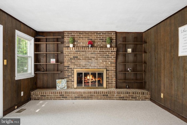 unfurnished living room with carpet flooring, a fireplace, and wooden walls