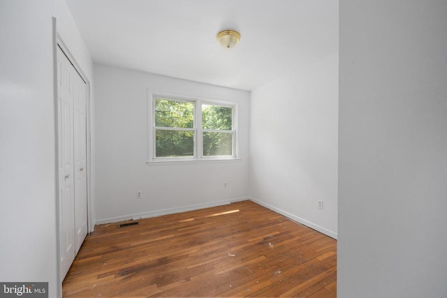 unfurnished bedroom with dark wood-type flooring and a closet