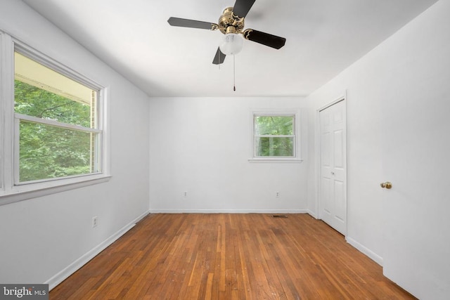 unfurnished room with plenty of natural light, ceiling fan, and wood-type flooring