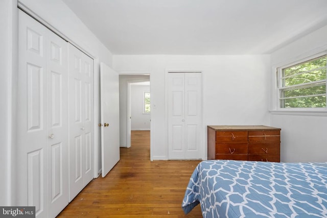 bedroom with multiple closets and light hardwood / wood-style flooring