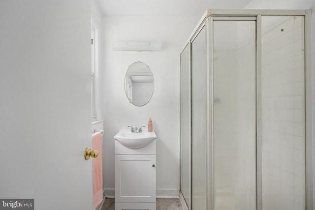 bathroom featuring a shower with shower door and vanity