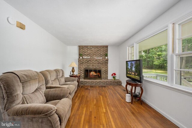 living room featuring wood-type flooring and a brick fireplace