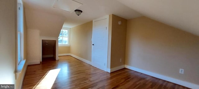 additional living space with hardwood / wood-style flooring and vaulted ceiling