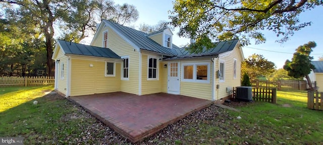 rear view of property with central AC, a patio area, and a lawn