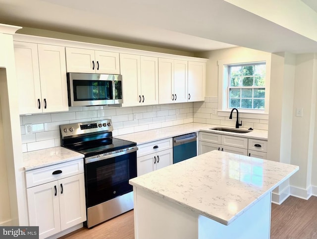 kitchen featuring a center island, sink, white cabinets, decorative backsplash, and stainless steel appliances