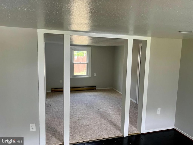 carpeted spare room featuring a baseboard radiator and a textured ceiling