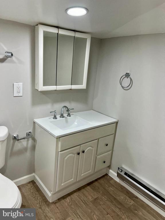 bathroom with vanity, toilet, wood-type flooring, and a baseboard radiator