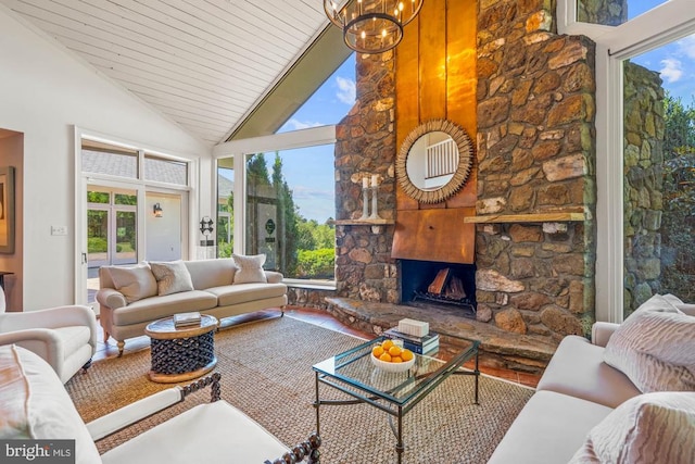 living room with hardwood / wood-style flooring, a fireplace, a notable chandelier, and high vaulted ceiling