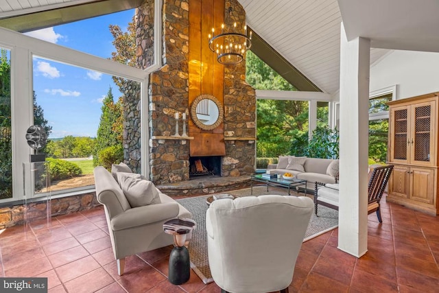 interior space featuring a notable chandelier, tile patterned flooring, high vaulted ceiling, and an outdoor stone fireplace