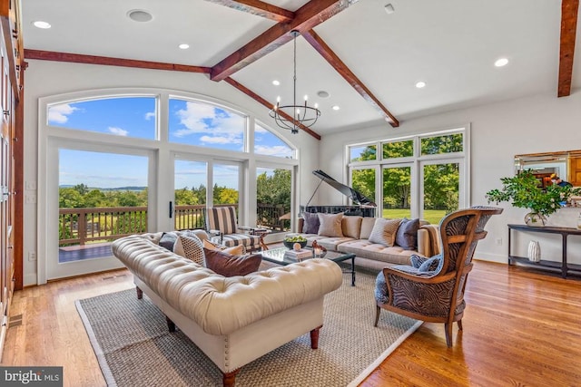 living room featuring beam ceiling, a chandelier, light hardwood / wood-style flooring, and a wealth of natural light