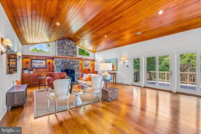 living room featuring light hardwood / wood-style floors, wooden ceiling, a fireplace, and a wealth of natural light