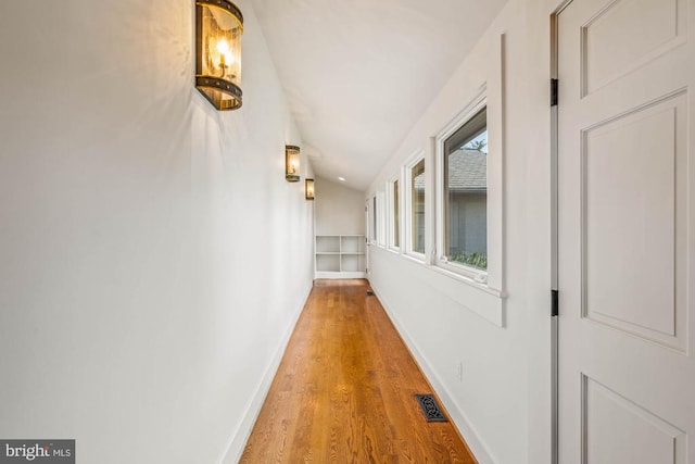 hall with vaulted ceiling and hardwood / wood-style flooring