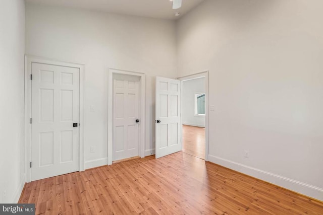 unfurnished bedroom featuring ceiling fan, light wood-type flooring, and high vaulted ceiling