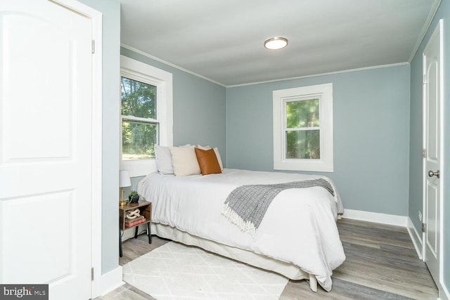 bedroom with wood-type flooring, multiple windows, and crown molding