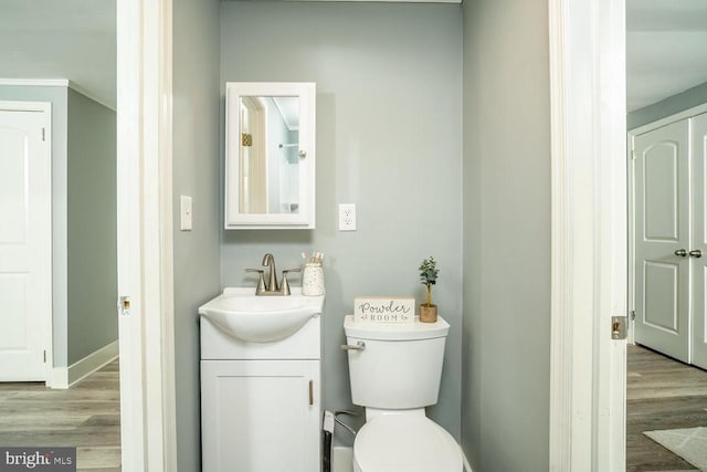 bathroom with ornamental molding, vanity, hardwood / wood-style floors, and toilet