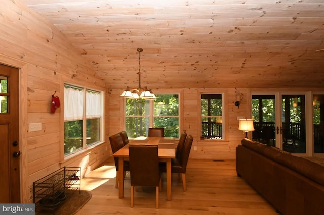 dining area featuring wood walls, wood ceiling, vaulted ceiling, and light hardwood / wood-style flooring