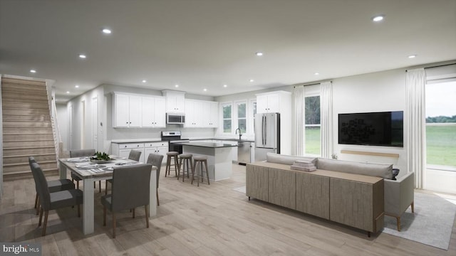 living room featuring a healthy amount of sunlight, sink, and light hardwood / wood-style flooring