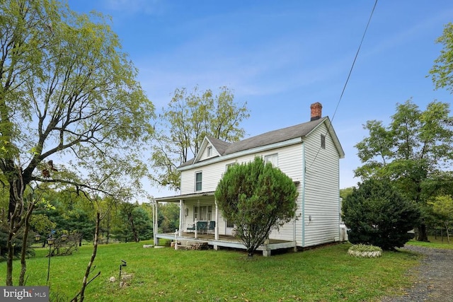 back of property with a yard and covered porch