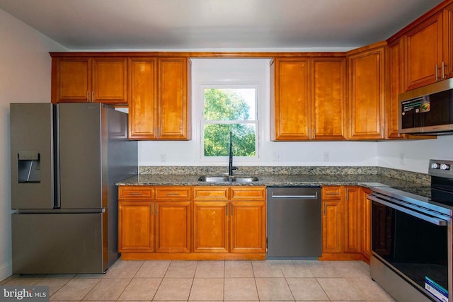 kitchen featuring dark stone counters, appliances with stainless steel finishes, sink, and light tile patterned floors