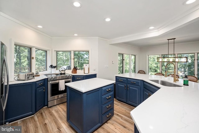 kitchen featuring a center island, sink, stainless steel appliances, decorative light fixtures, and blue cabinetry