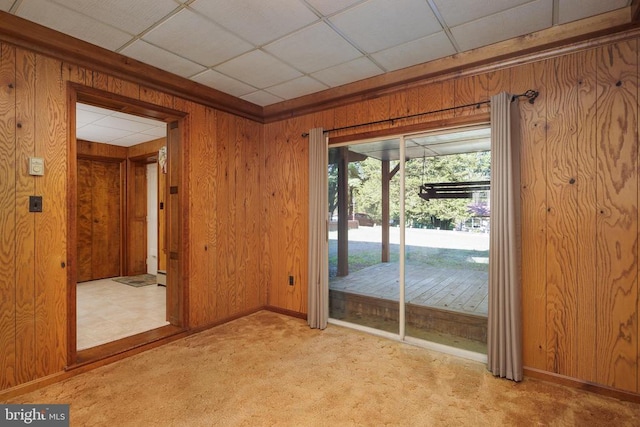 entryway with light carpet, wooden walls, and a paneled ceiling