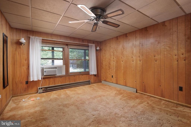 carpeted empty room with ceiling fan, cooling unit, wooden walls, a baseboard heating unit, and a drop ceiling