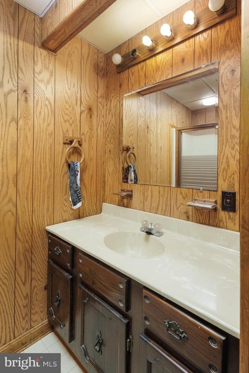 bathroom with tile patterned flooring, vanity, and wooden walls