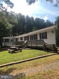 rear view of property featuring a lawn and a deck