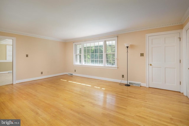 empty room featuring light wood-type flooring, crown molding, and radiator heating unit