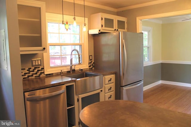 kitchen with ornamental molding, tasteful backsplash, white cabinetry, stainless steel appliances, and hardwood / wood-style floors