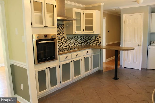 kitchen featuring crown molding, oven, tasteful backsplash, and white cabinets