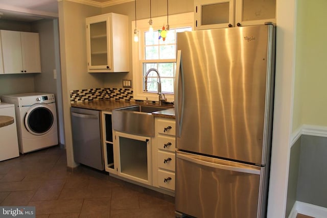 kitchen featuring pendant lighting, sink, white cabinetry, washer and clothes dryer, and appliances with stainless steel finishes