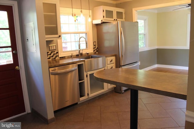 kitchen featuring white cabinets, stainless steel appliances, dark tile patterned floors, decorative light fixtures, and sink