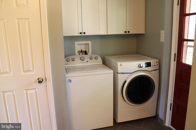 laundry room with cabinets, dark tile patterned flooring, and washer and clothes dryer