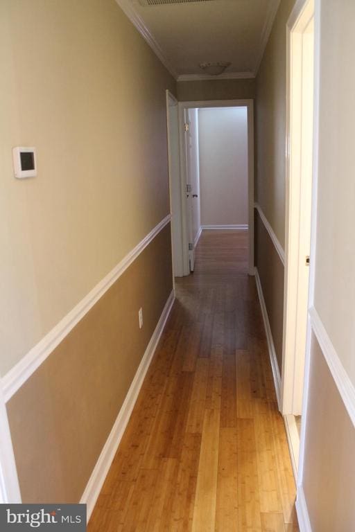 hallway featuring ornamental molding and hardwood / wood-style floors