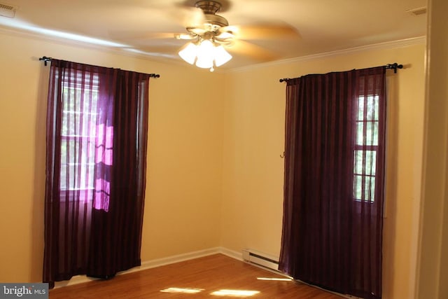 empty room with a wealth of natural light, wood-type flooring, and ceiling fan