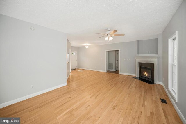 unfurnished living room with ceiling fan, a textured ceiling, and light hardwood / wood-style flooring